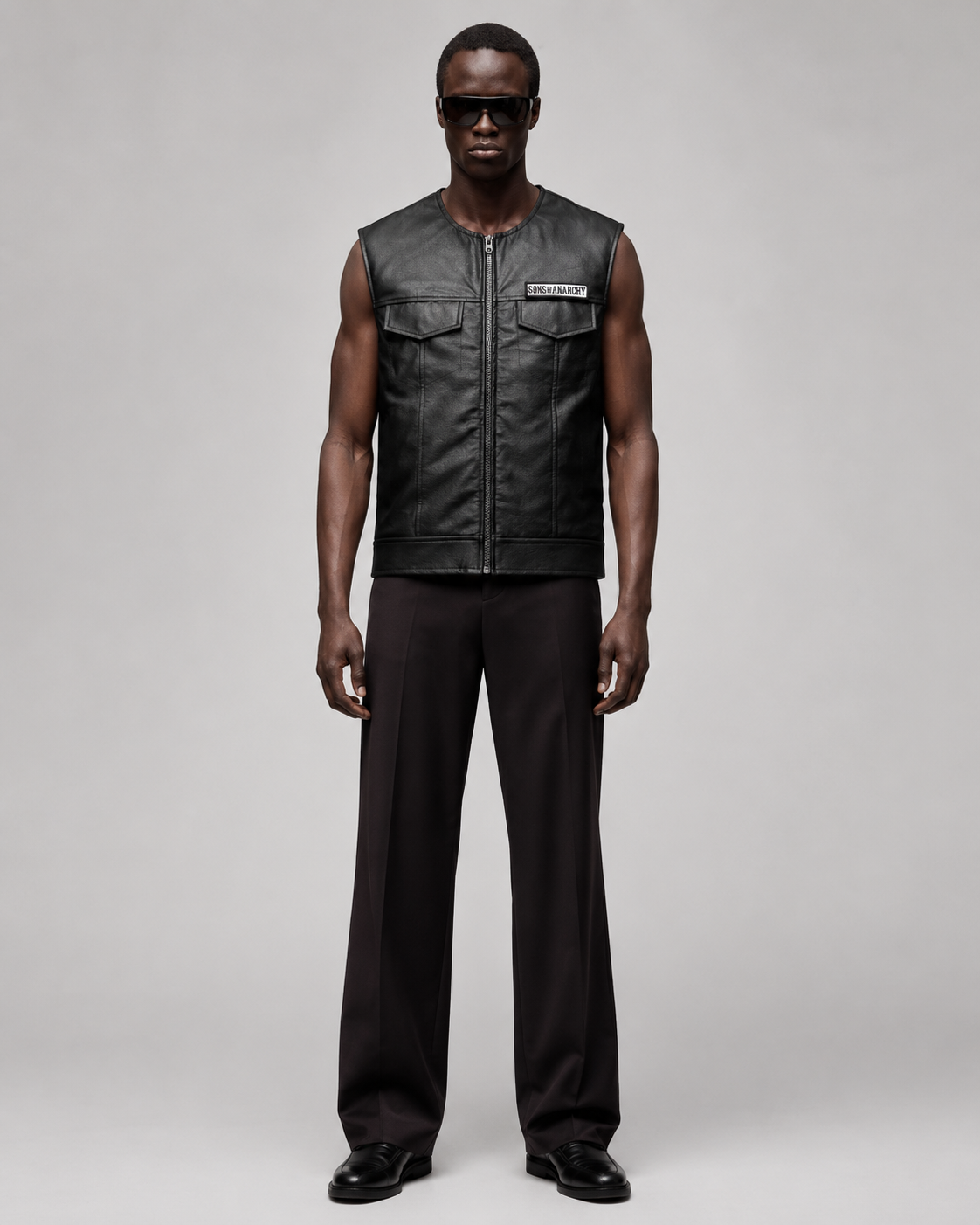 Men's black leather vest with Sons of Anarchy patch, paired with dark trousers and sunglasses