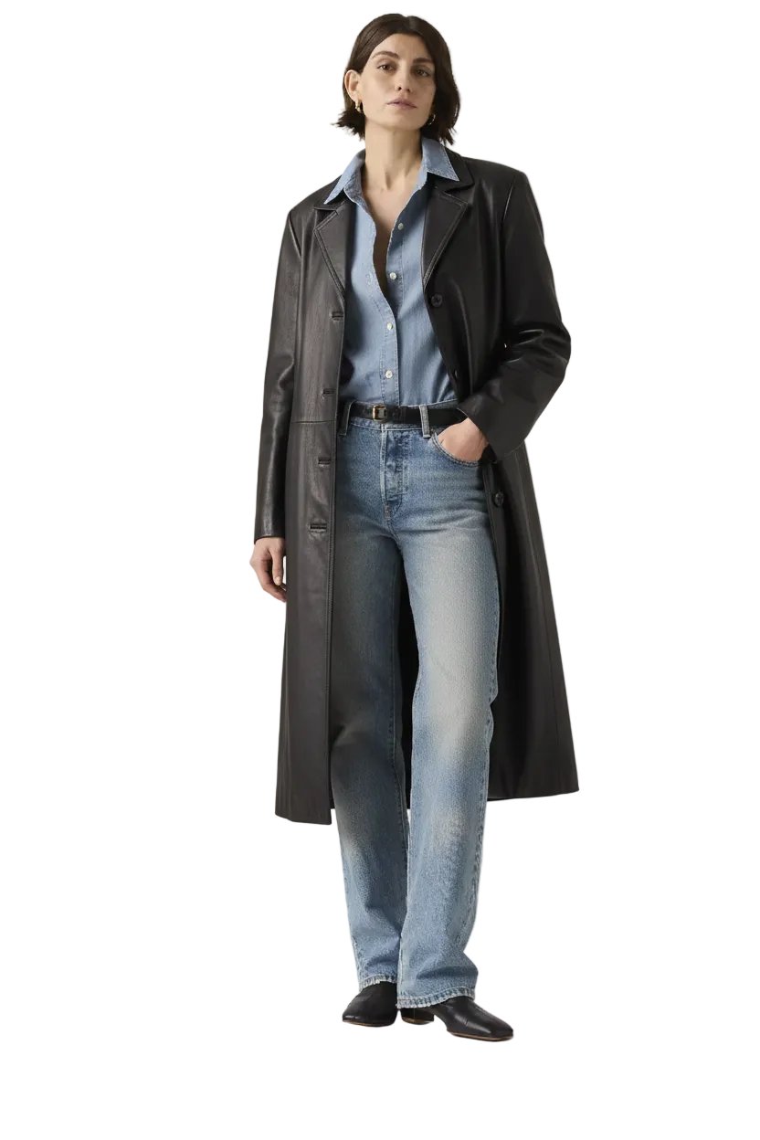 Woman wearing black leather trench coat over denim shirt and jeans