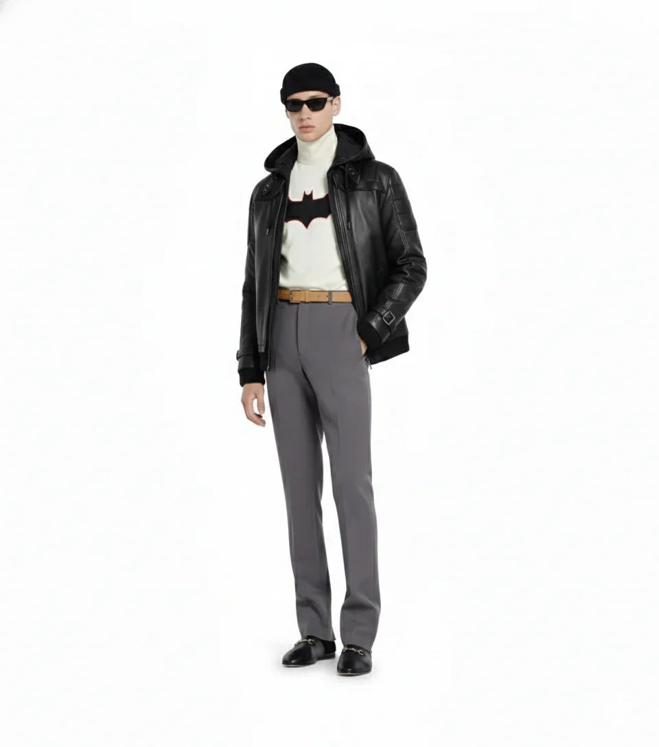 Man wearing black leather jacket, Batman graphic turtleneck, gray trousers, and sunglasses