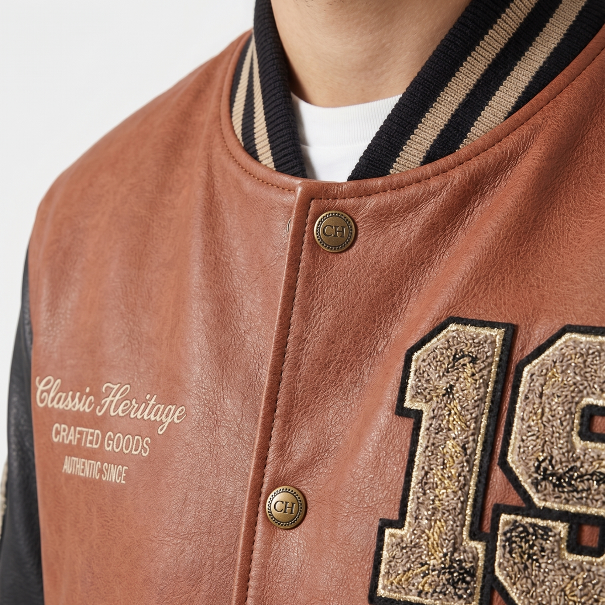 Brown leather jacket with embroidered text and buttons on a white background