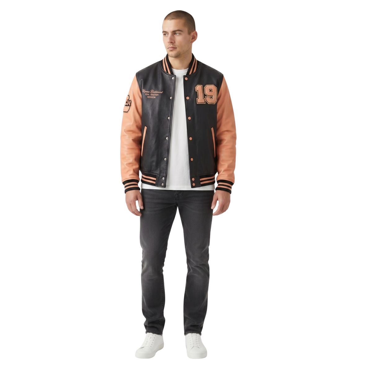 Man wearing a two-tone varsity jacket with black and orange sleeves, white shirt, and dark jeans on a white background.
