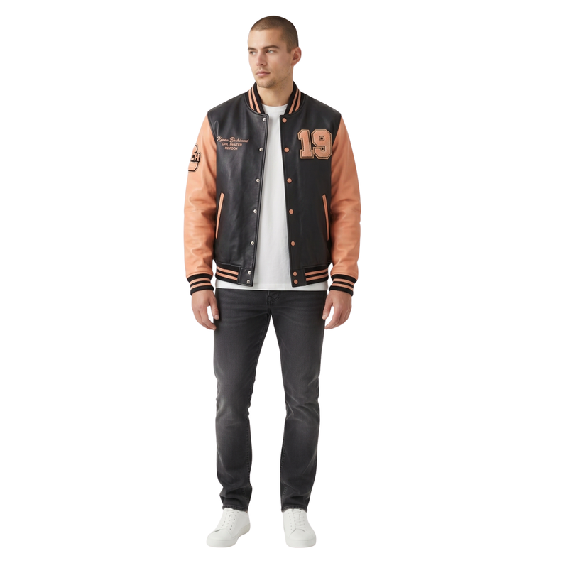 Man wearing a two-tone varsity jacket with black and orange sleeves, white shirt, and dark jeans on a white background.