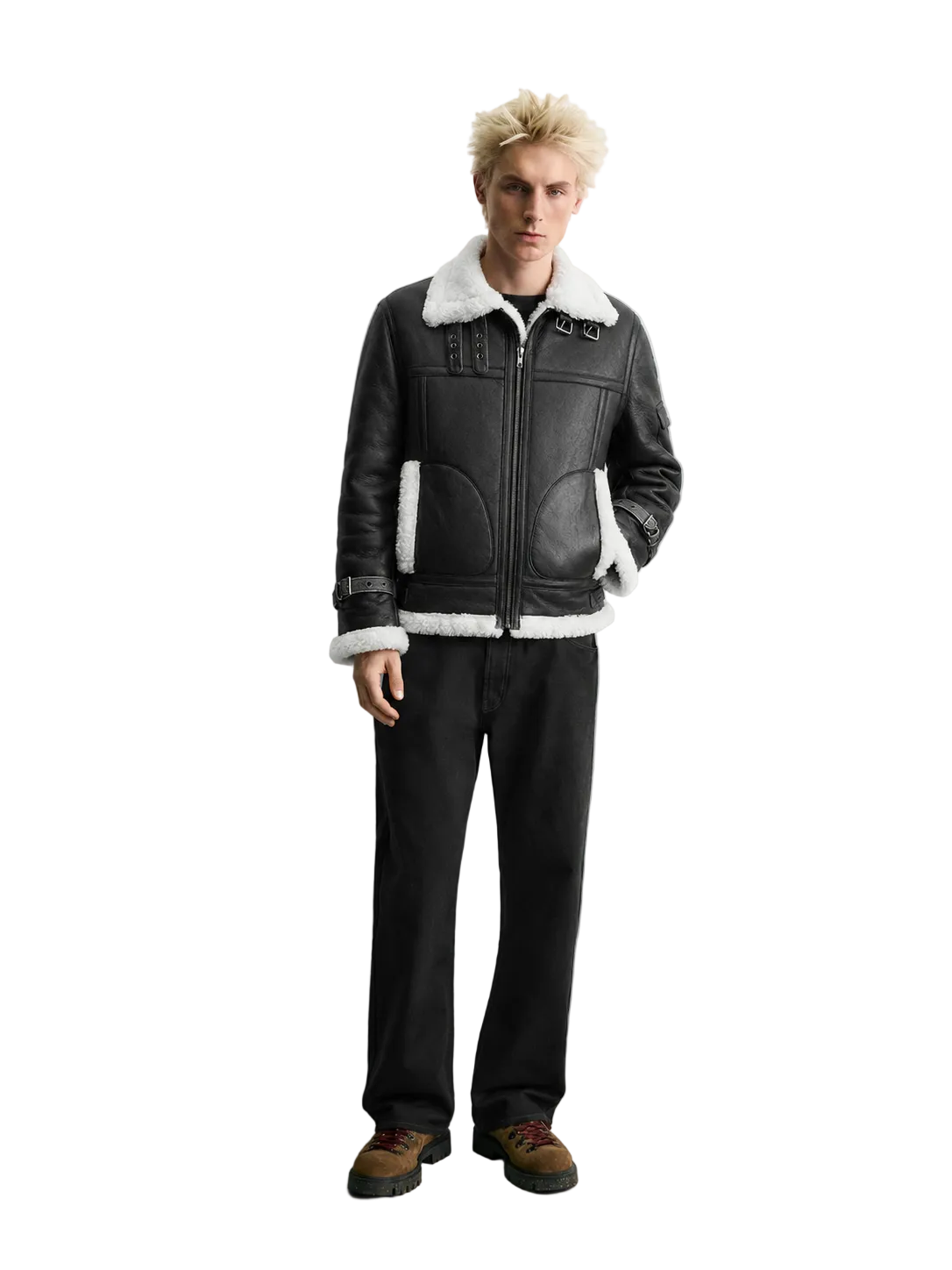 A model stands against a light gray studio background wearing a black leather aviator-style jacket with white shearling lining, black jeans, and brown shoes.