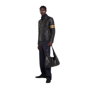 Men's black leather jacket with gold stripes, styled with navy pants and a matching leather bag