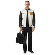 Men's varsity jacket with leather sleeves, gold number 19, and black pants, holding a sleek black briefcase