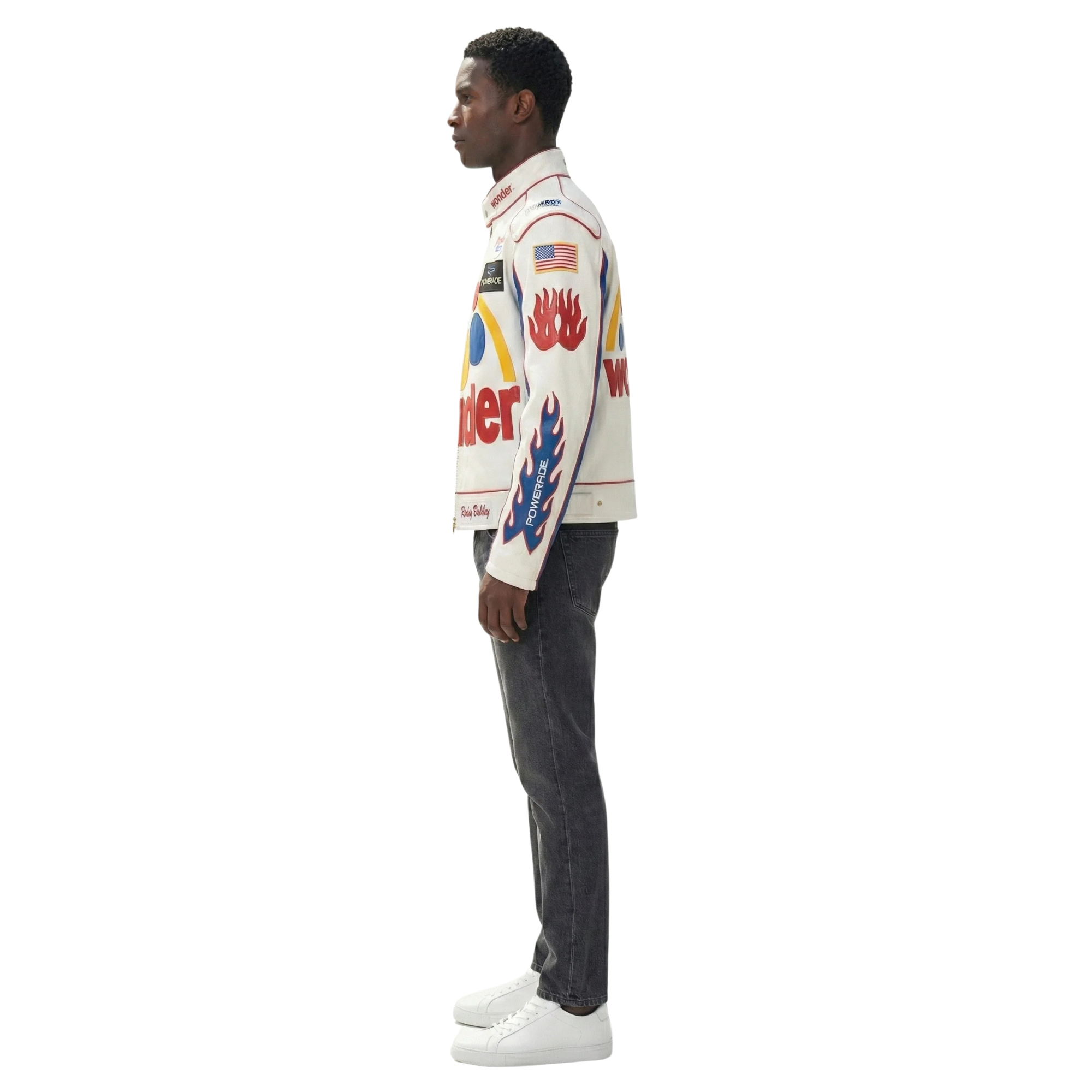 Man wearing white racing jacket with flame graphics, American flag, and sponsor logos, paired with dark jeans and white sneakers
