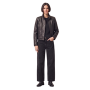 Woman in black leather jacket, ribbed sweater, wide-leg jeans, and boots, hands in pockets, studio shot
