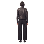 Woman wearing black leather jacket and wide-leg jeans, back view