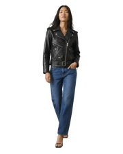 Woman in black leather moto jacket with belt, paired with blue jeans and heels