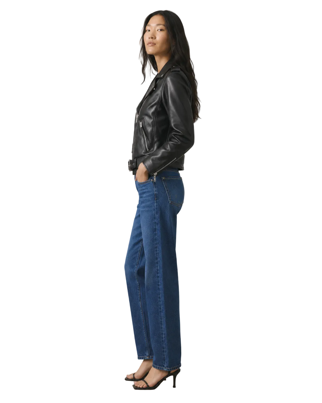 Woman in black leather moto jacket and wide-leg blue jeans, side view