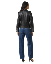 Woman wearing black leather moto jacket with zipper details, paired with wide-leg blue jeans and heels