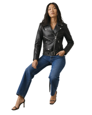 Woman in black leather moto jacket, blue jeans, and heels, posing confidently