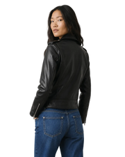 Woman wearing black leather moto jacket with zipper details, paired with blue jeans, back view