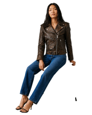 Woman in brown leather moto jacket, blue jeans, and black heels, stylish casual outfit