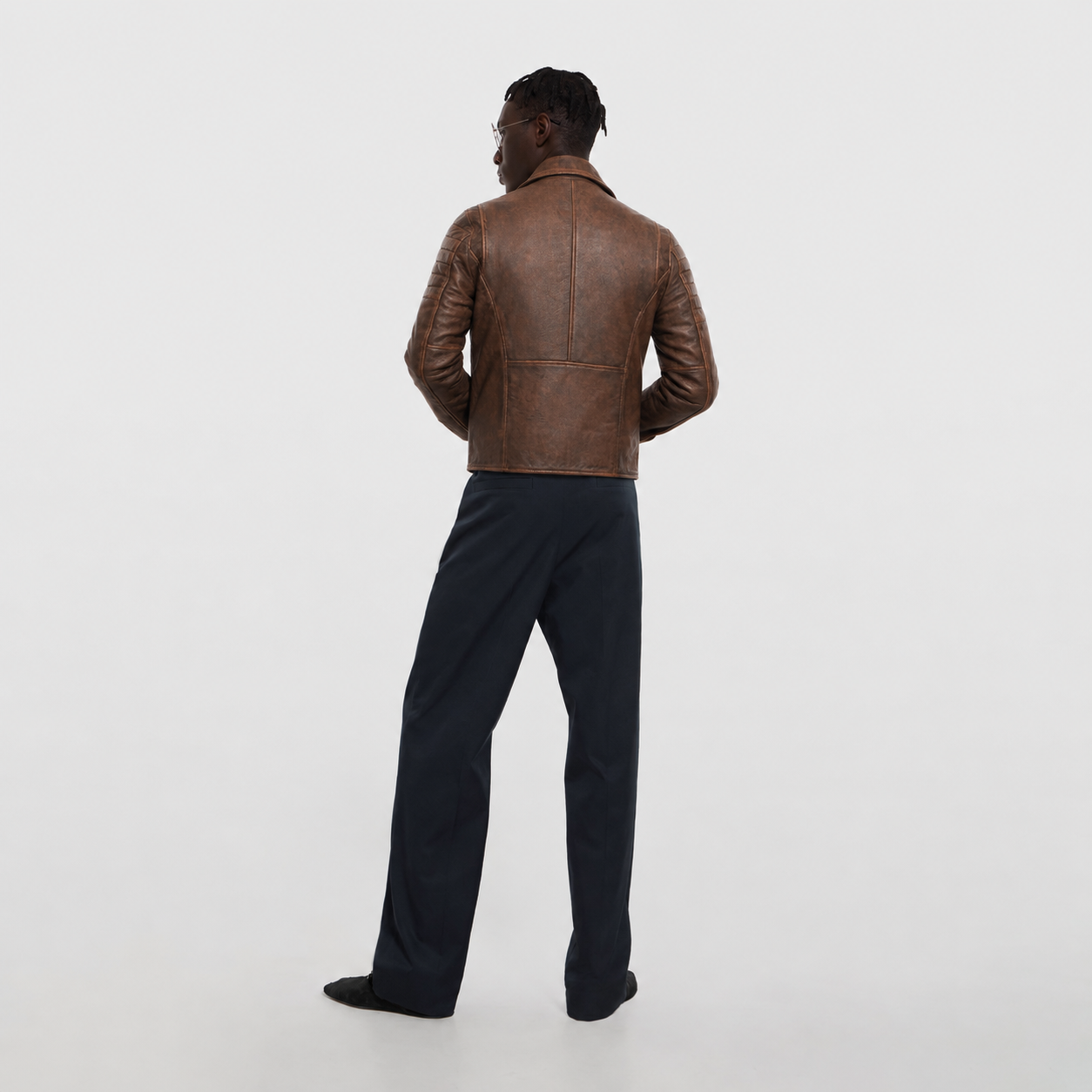 Men's brown leather jacket with quilted sleeves, back view, paired with dark trousers