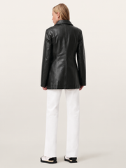 Black leather jacket with structured back, worn with white pants and chunky sneakers