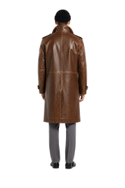 Men's brown leather trench coat with classic back view, paired with gray trousers and black beanie