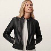 Woman wearing black leather moto jacket with zipper details over cream sweater