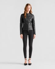 Woman in black leather moto jacket with zipper details, paired with skinny jeans and heels