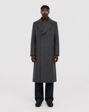 Men's gray double-breasted wool coat with patterned texture, worn with dark trousers and loafers