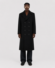 Men's black double-breasted long coat with wide lapels, styled with dark trousers and loafers