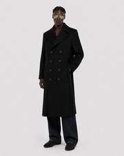 Men's black double-breasted long coat with wide lapels, styled with dark trousers and loafers