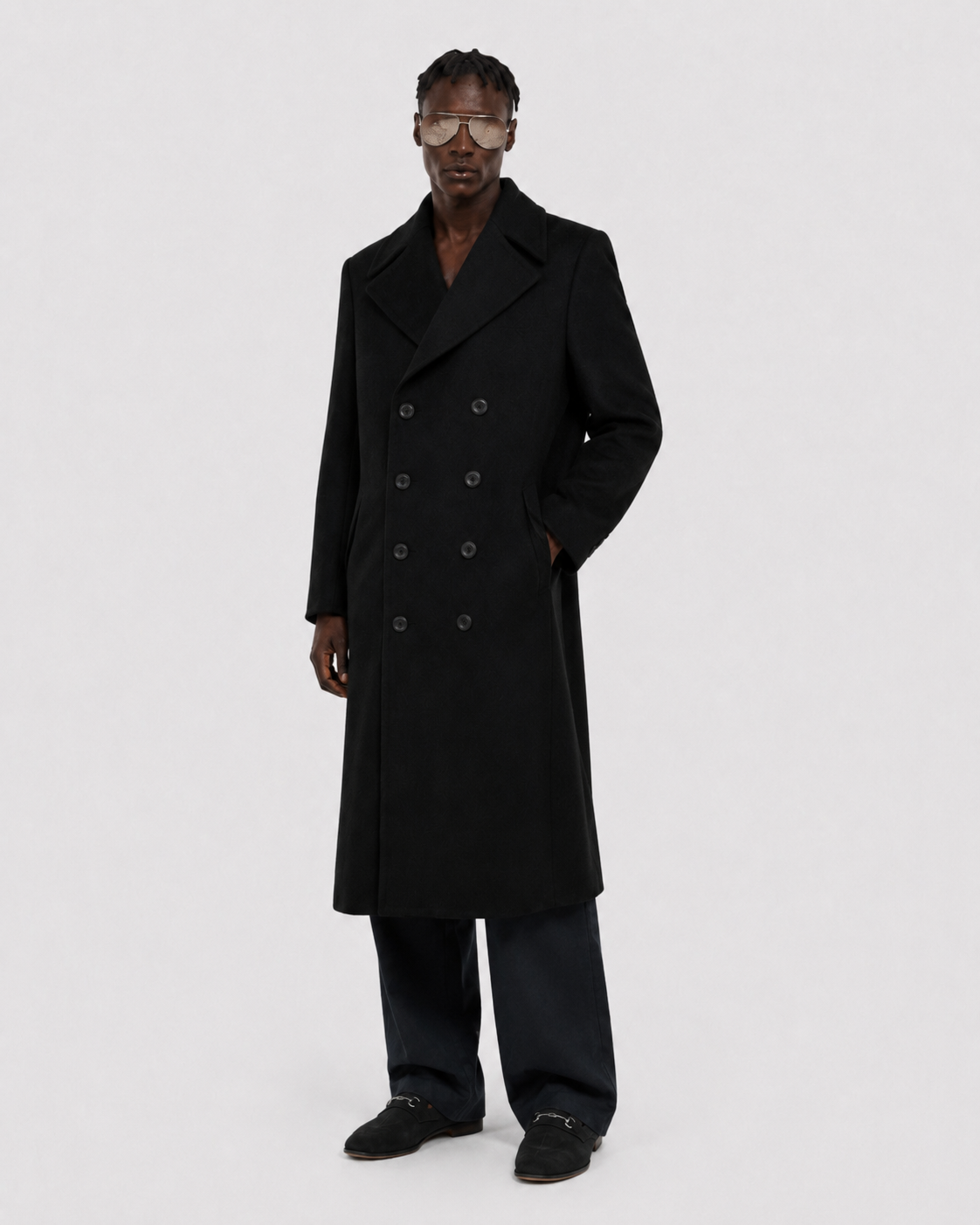 Men's black double-breasted long coat with wide lapels, styled with dark trousers and loafers