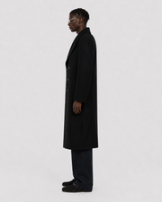 Man in black double-breasted wool coat, side profile, minimalist studio look
