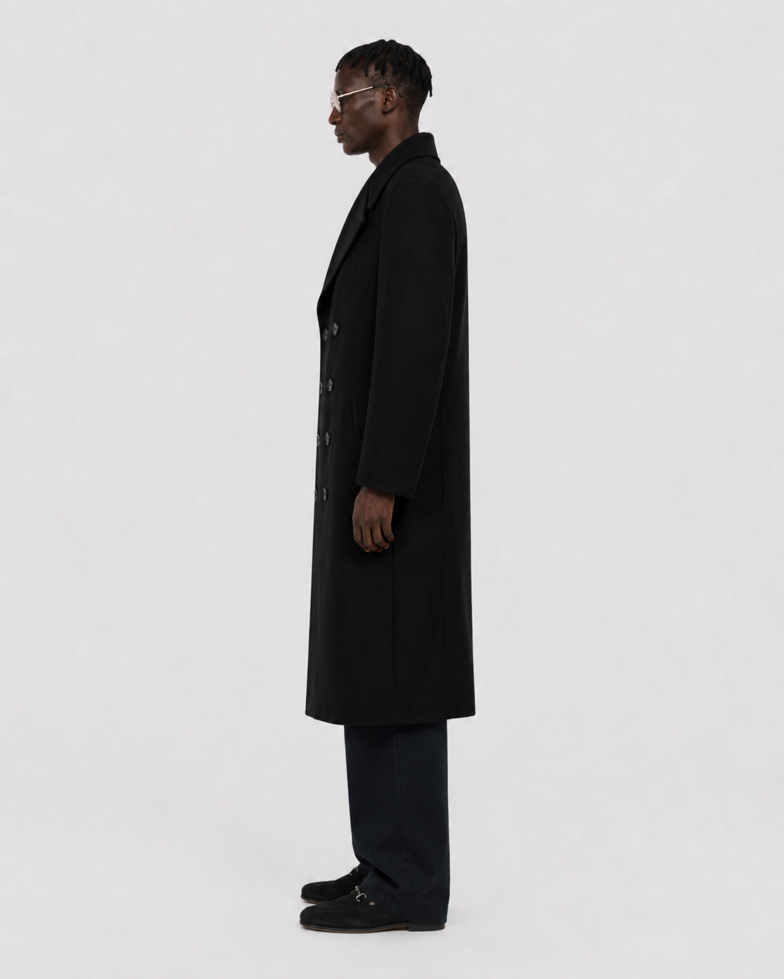 Man in black double-breasted wool coat, side profile, minimalist studio look