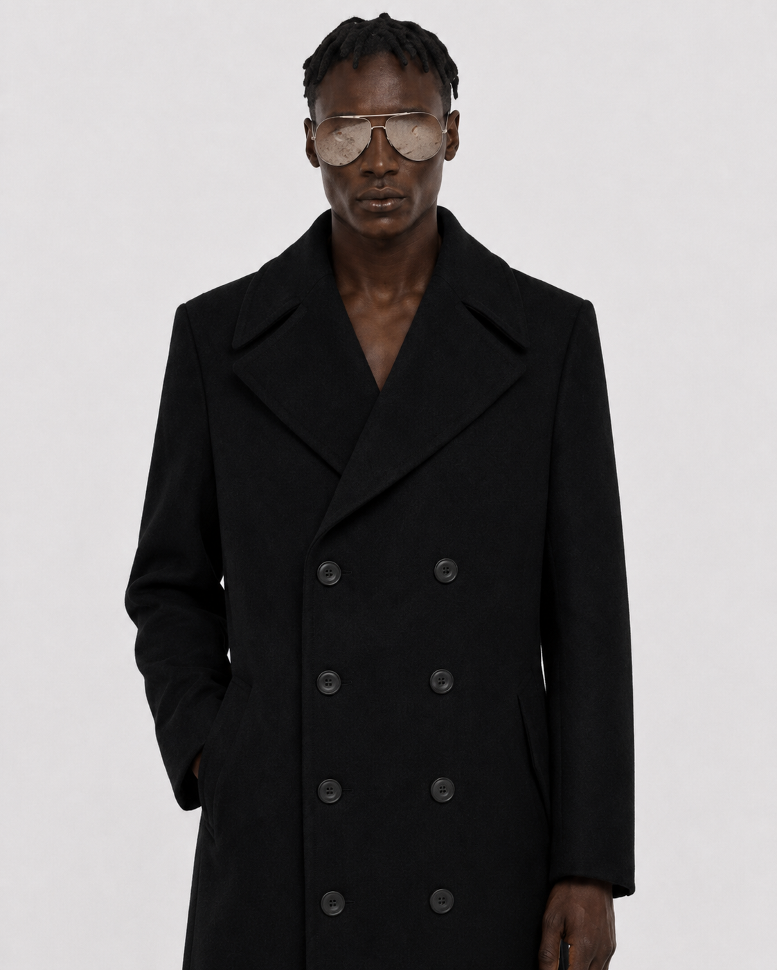 Men's black double-breasted wool coat with wide lapels and six-button front, styled with aviator sunglasses.