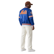 Blue Mets varsity jacket with orange lettering, striped cuffs, and team logo, worn with white pants and cap