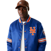 Blue New York Mets satin varsity jacket with orange logo and striped sleeves, worn with brown cap