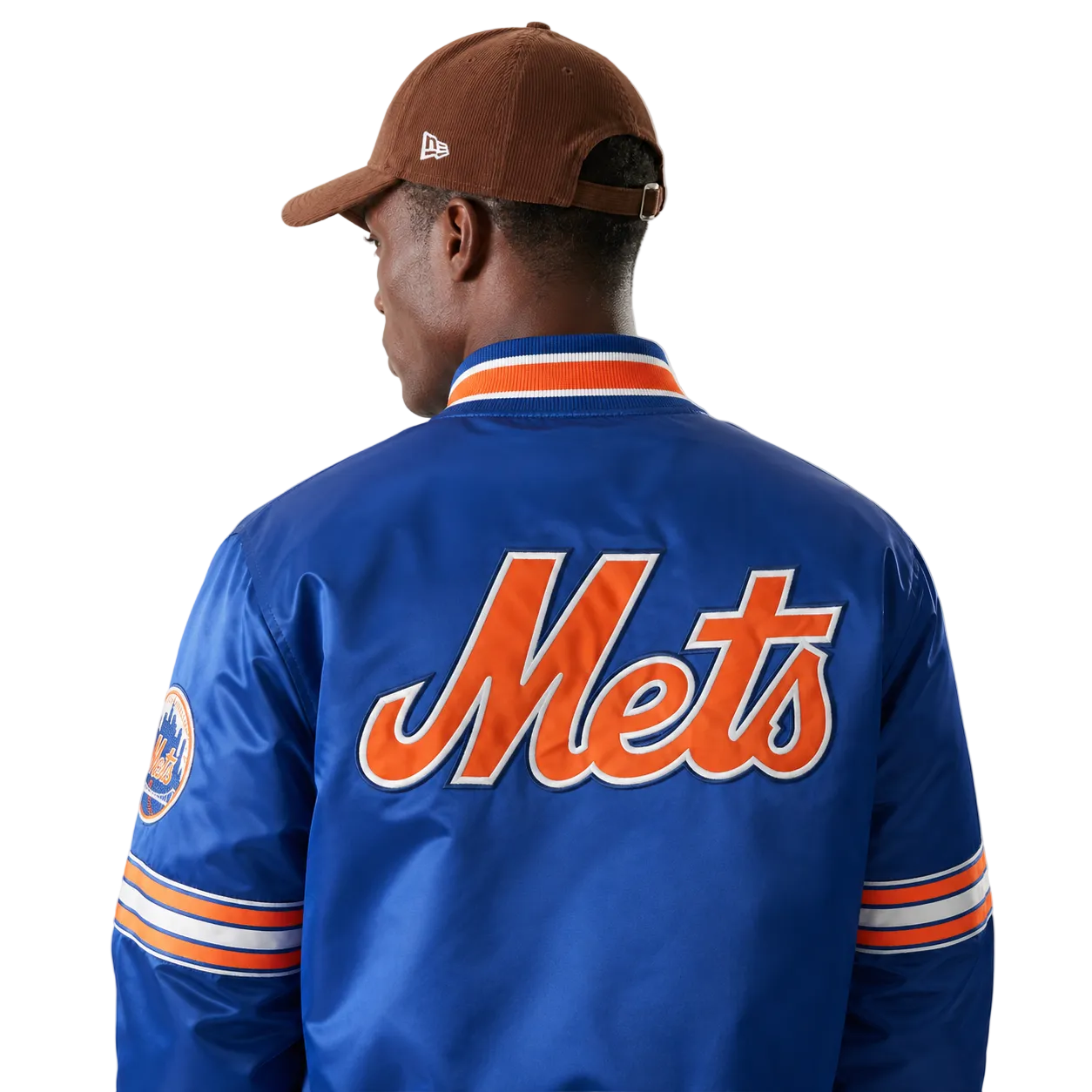 Blue Mets varsity jacket with orange script logo, striped sleeves, and team patch, worn with brown cap