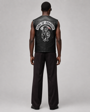 Black leather vest with Sons of Anarchy skull logo, worn by man in dark pants, back view