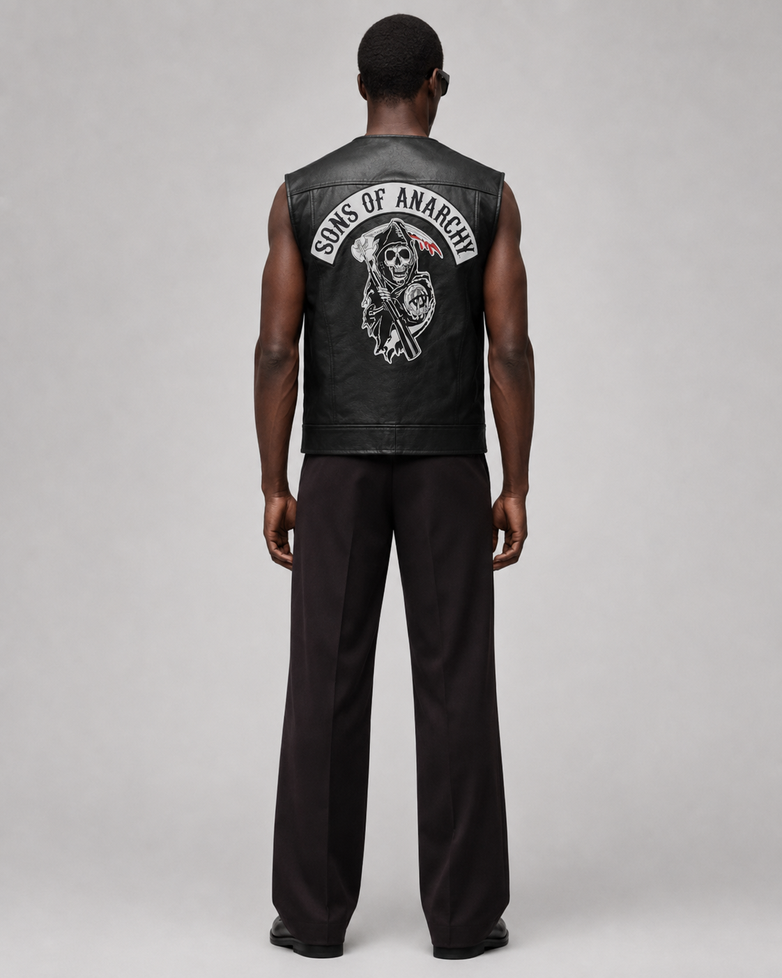 Black leather vest with Sons of Anarchy skull logo, worn by man in dark pants, back view