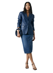 Woman in blue leather blazer and denim midi skirt with matching clutch and black heels