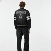 Black Cowboys varsity jacket with star logo, striped sleeves, and back text, worn by model in studio