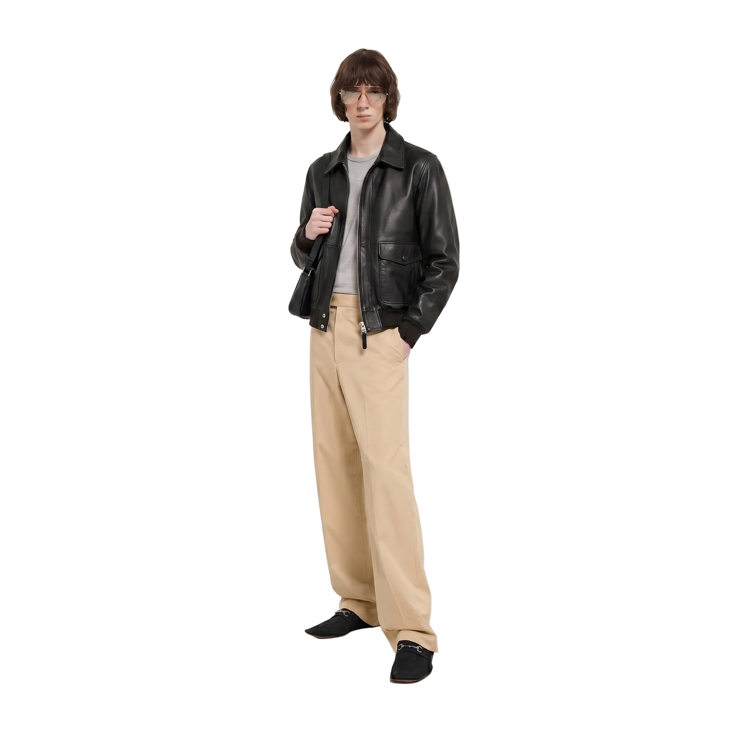 Person wearing a black leather jacket, beige pants, and black shoes on a white background