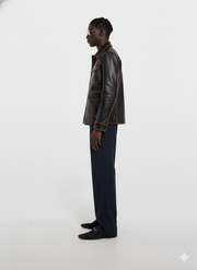 Man in black leather jacket with contrast stitching, navy trousers, and loafers, side profile