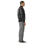 Men's black leather bomber jacket with patch, paired with gray jeans and sneakers