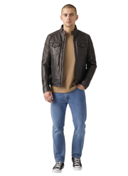 Man wearing dark brown leather jacket, beige shirt, blue jeans, and black sneakers