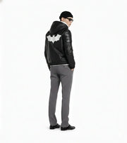 Men's black leather jacket with white bat emblem, styled with gray pants and beanie