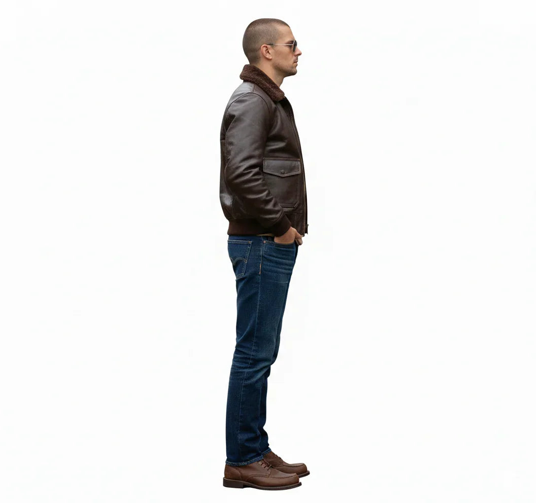 Man in brown leather bomber jacket with shearling collar, blue jeans, and brown shoes, side view