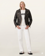 Woman in black leather biker jacket, white sweater, and white jeans, stylish casual outfit