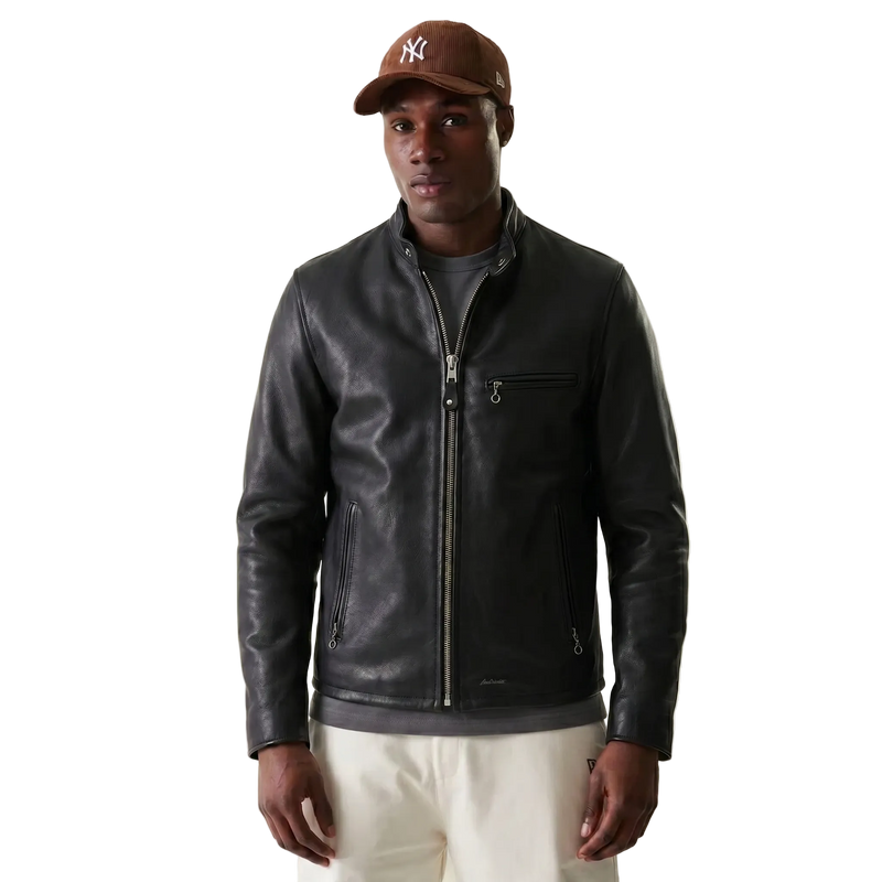 Man wearing a black leather jacket and a brown cap on a beige background