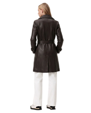 Black leather trench coat with belt, worn with white pants and sneakers, back view