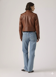 Woman wearing brown leather moto jacket and light wash denim jeans, back view