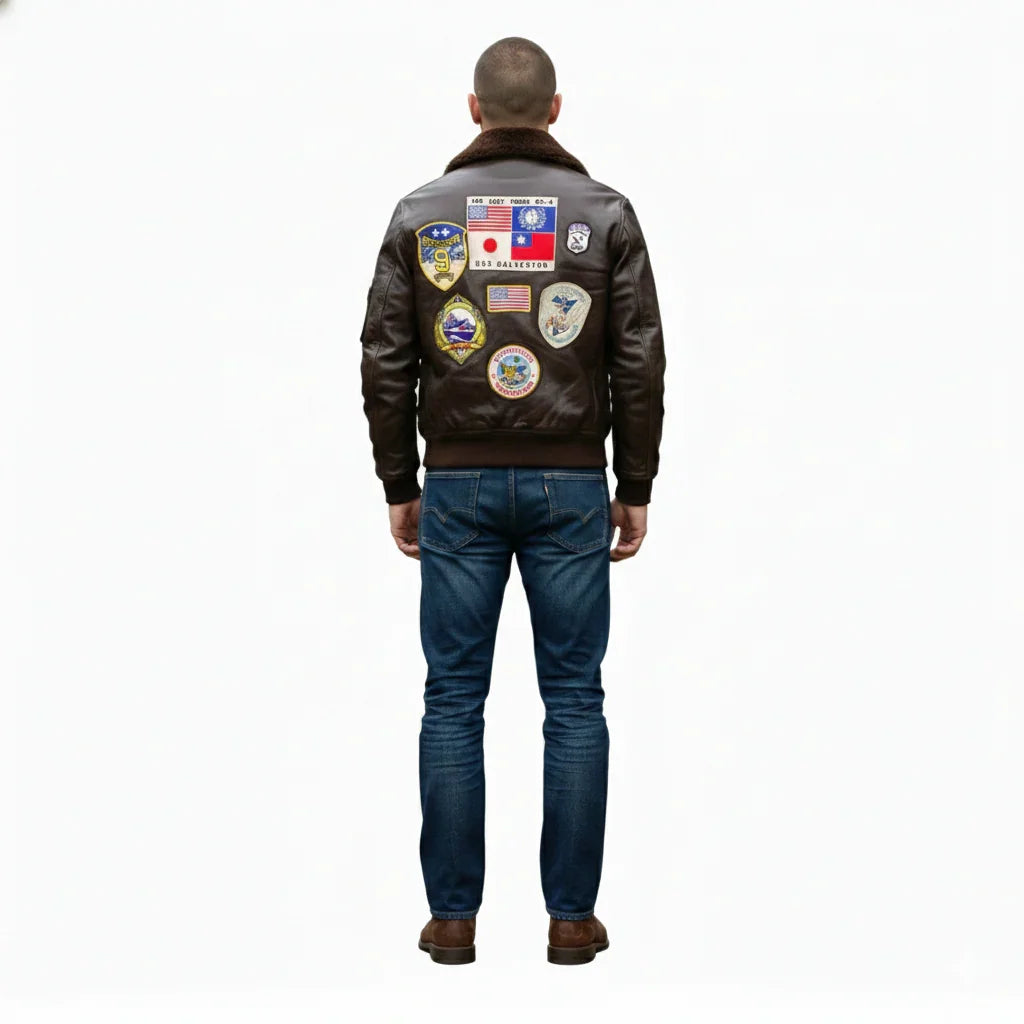 Men's brown leather bomber jacket with vintage aviation patches, worn with blue jeans