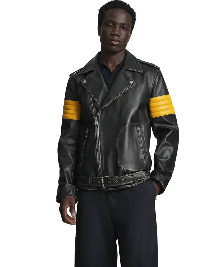 Man wearing a black leather jacket with yellow stripes on a gray background