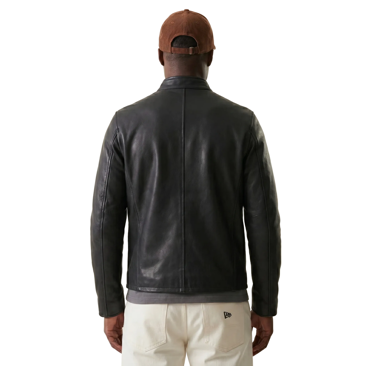 Person wearing a black leather jacket and brown cap on a beige background